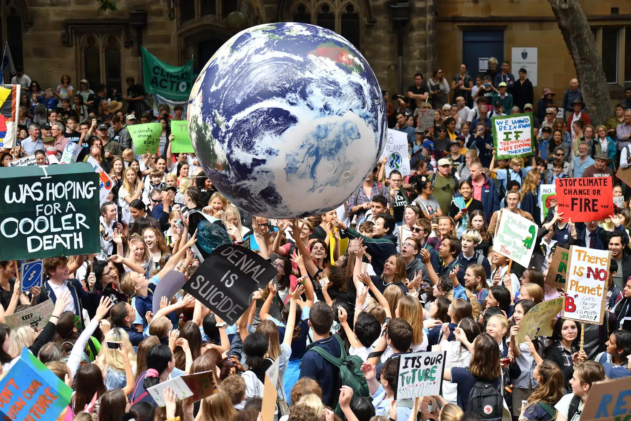 large crowd of young adults at global climate protest, playing with a large inflatable ball toy earth, credit reuters